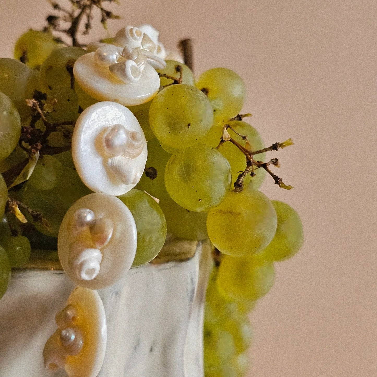 Bouquet of green grapes with decorative white pearls on a beige background