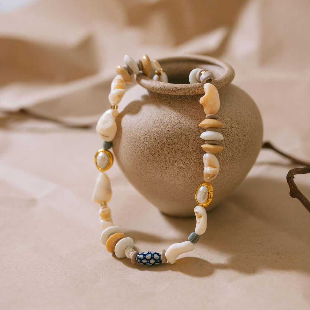Beaded bracelet with natural stones on a beige ceramic vase against a soft beige background