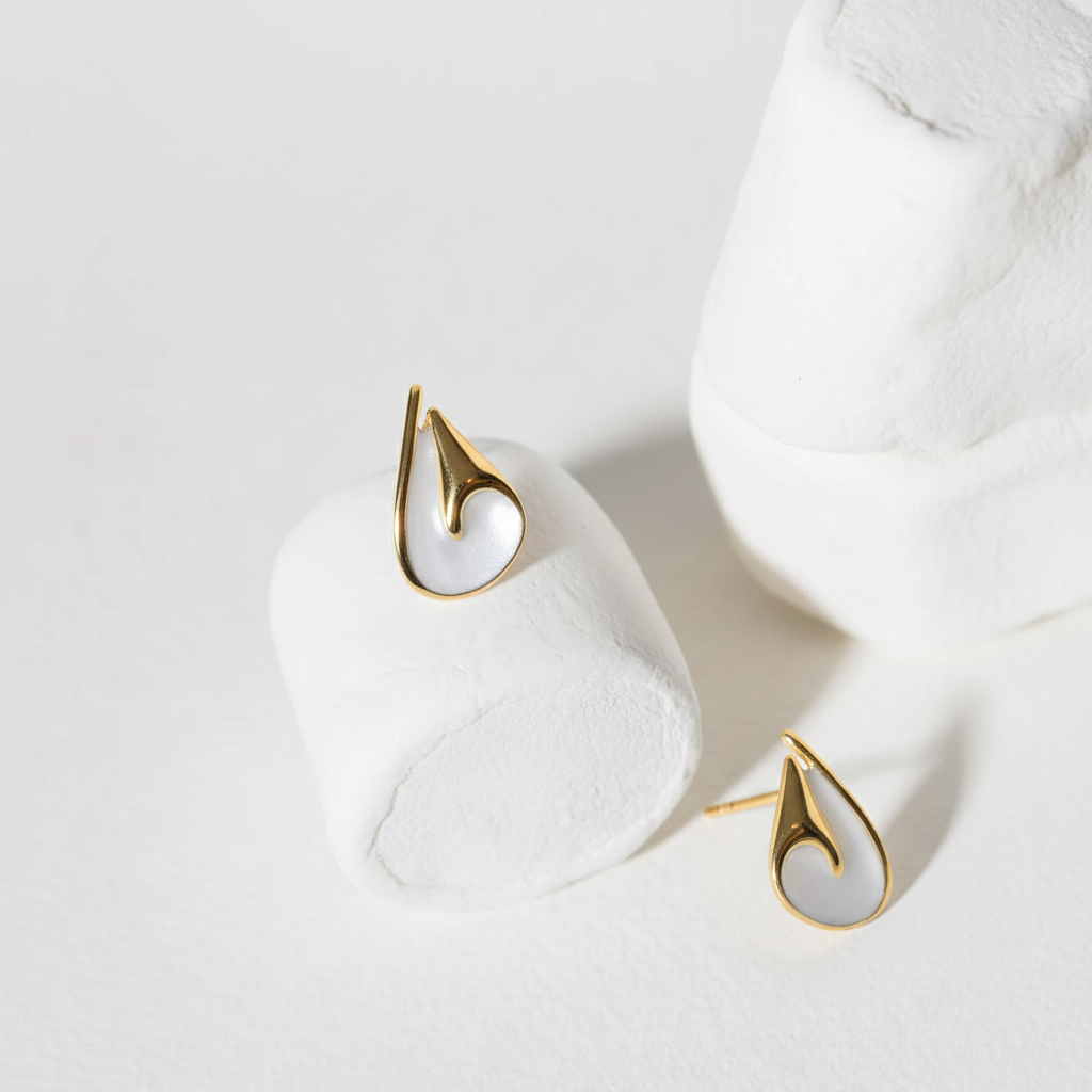 Gold and white earrings on a light gray background
