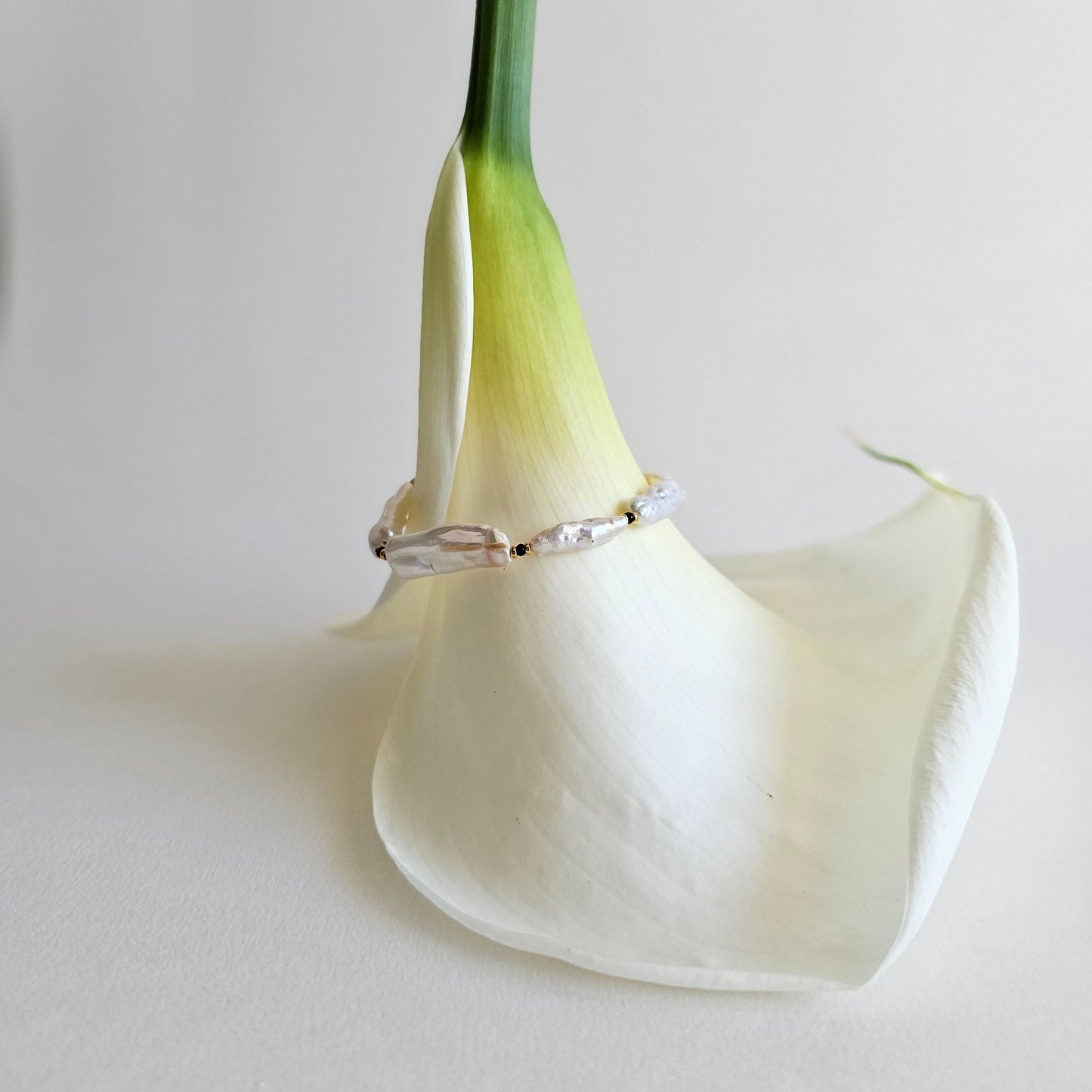 Silver ring on a white calla lily against a light gray background