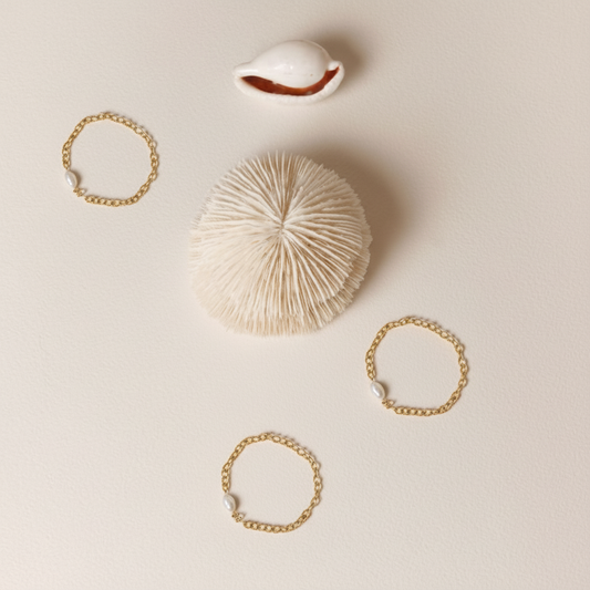 Gold rings and a shell on a beige surface