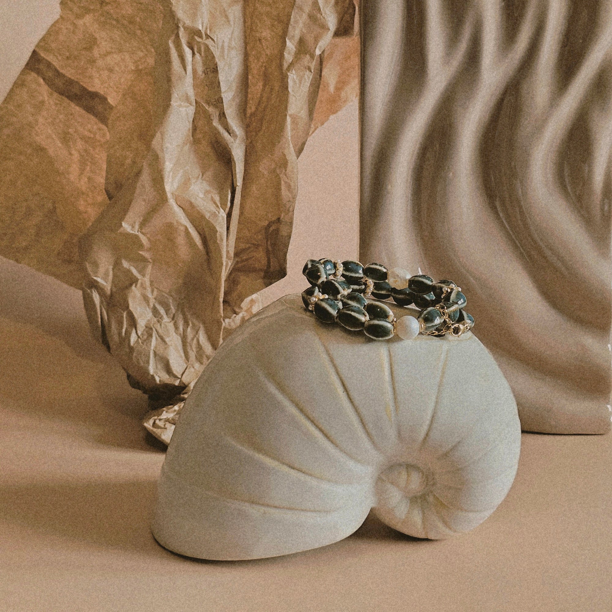 Bracelet on a shell with a rock and textured wall in the background