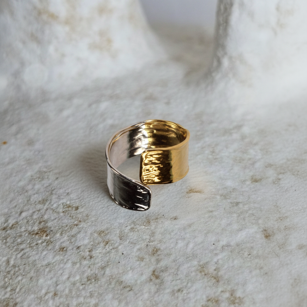 Gold and silver ring on a textured beige surface